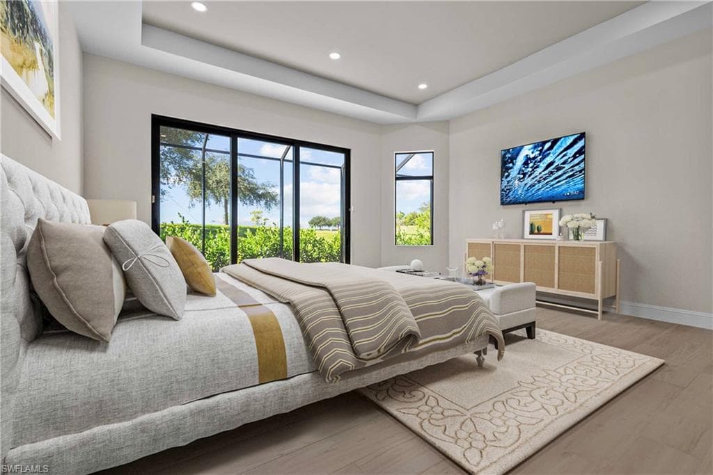 Bedroom featuring a tray ceiling, light wood-style floors, recessed lighting, and access to exterior