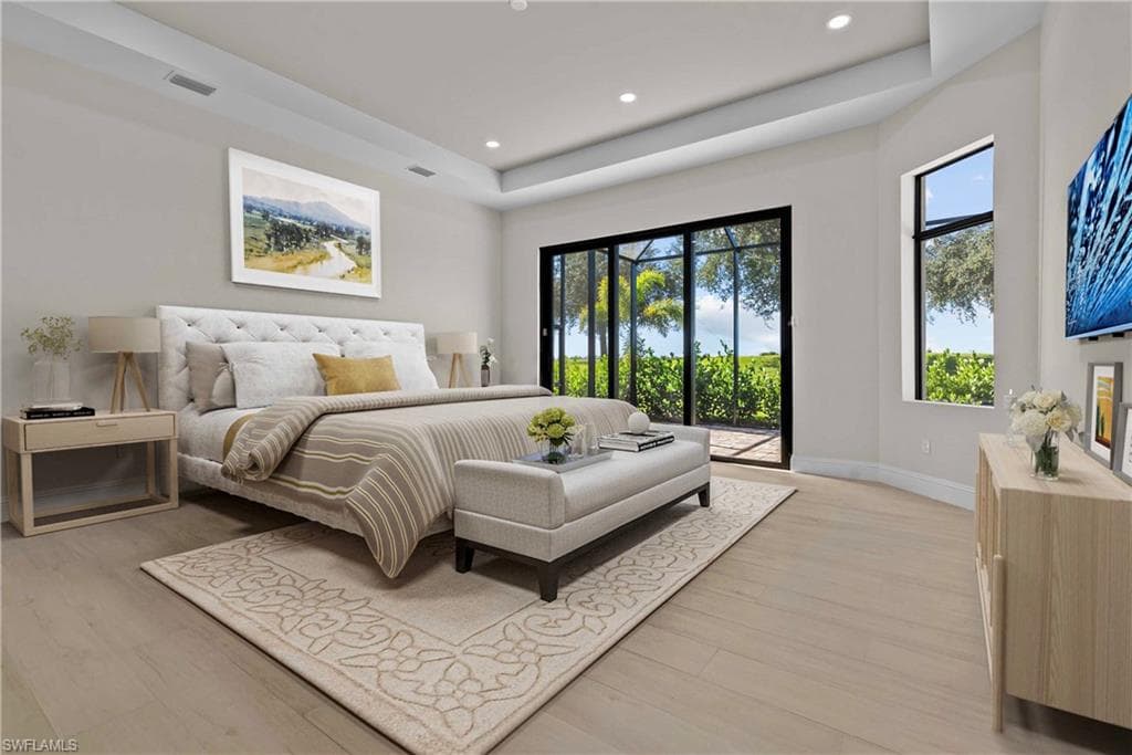 Bedroom with a raised ceiling, access to outside, light wood-style flooring, and recessed lighting