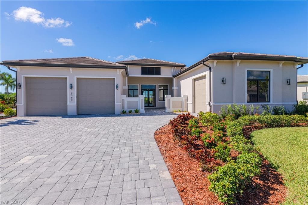 Prairie-style house with stucco siding, a garage, and decorative driveway