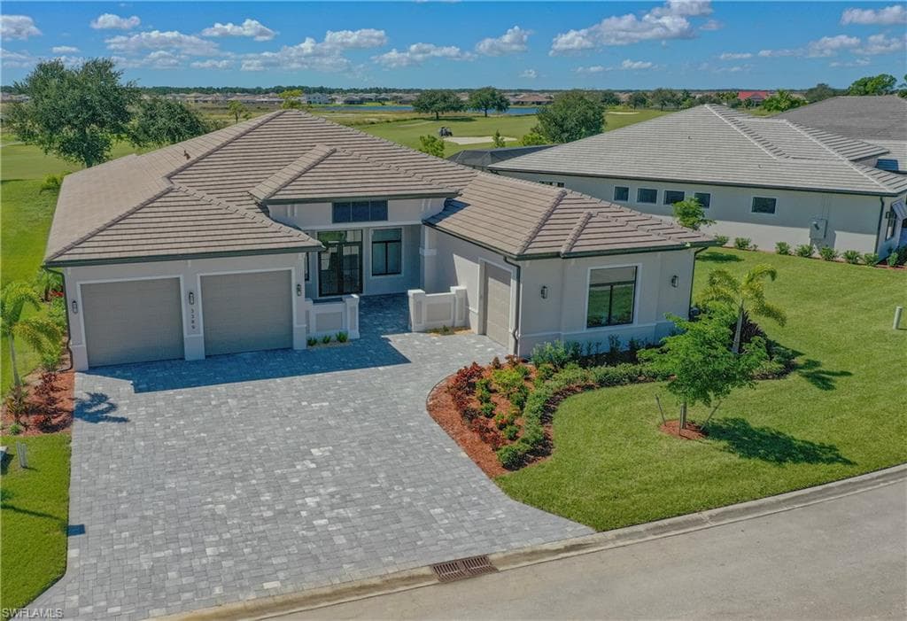 View of front of house featuring an attached garage, decorative driveway, a front lawn, and stucco siding