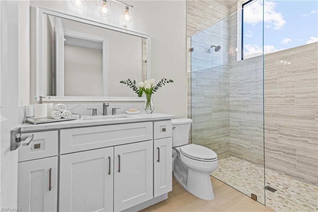 Full bathroom with walk in shower, vanity, and light wood-style floors