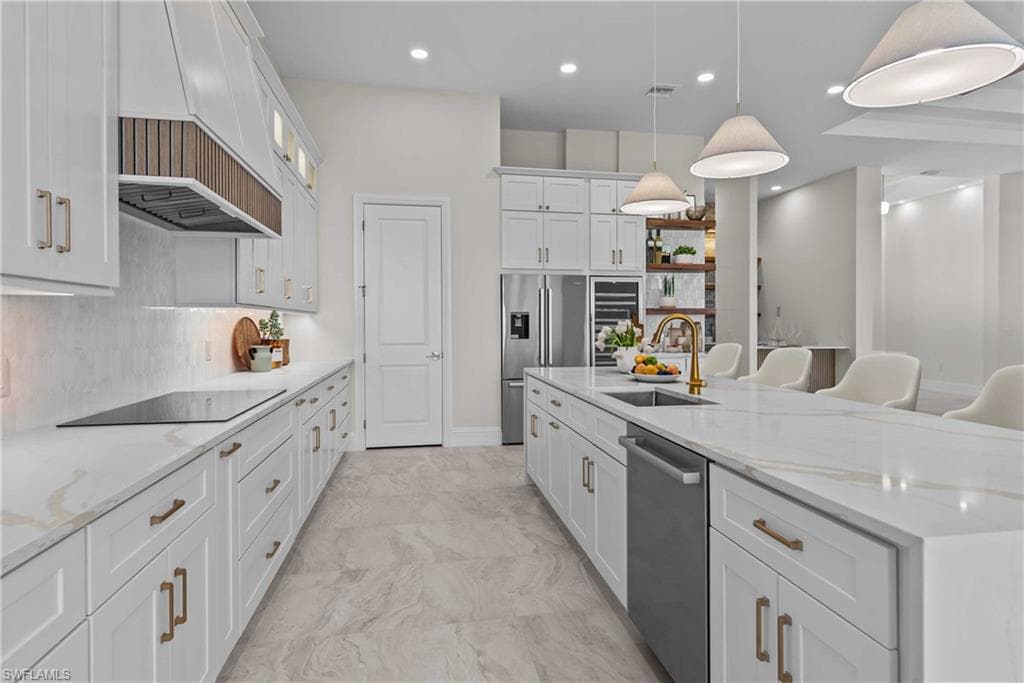Kitchen featuring light stone countertops, white cabinets, tasteful backsplash, a kitchen breakfast bar, and recessed lighting