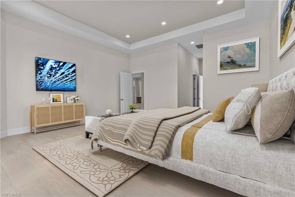 Bedroom with a tray ceiling, wood finished floors, and recessed lighting