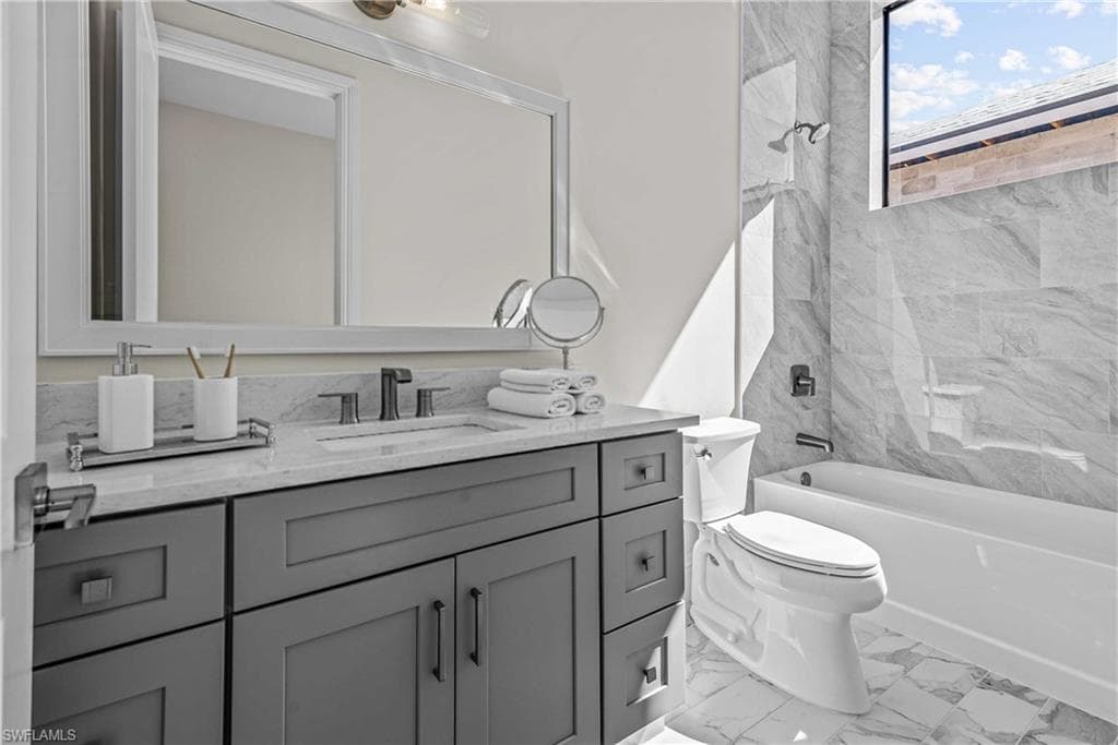 Bathroom with vanity, shower / tub combination, and light marble finish flooring