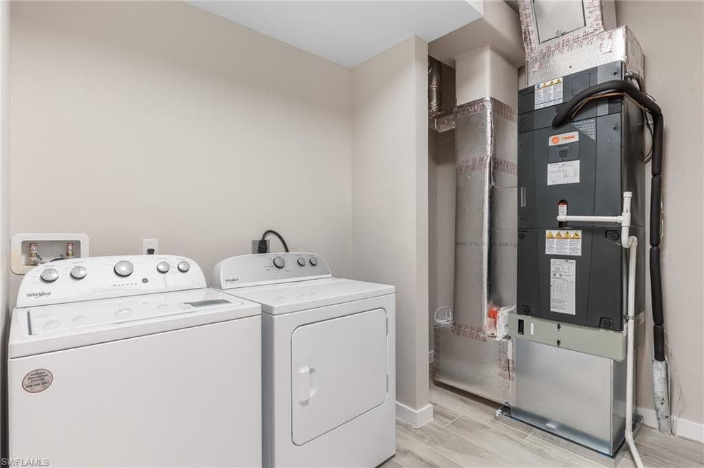 Laundry room with heating unit, wood tiled floors, and washer and clothes dryer