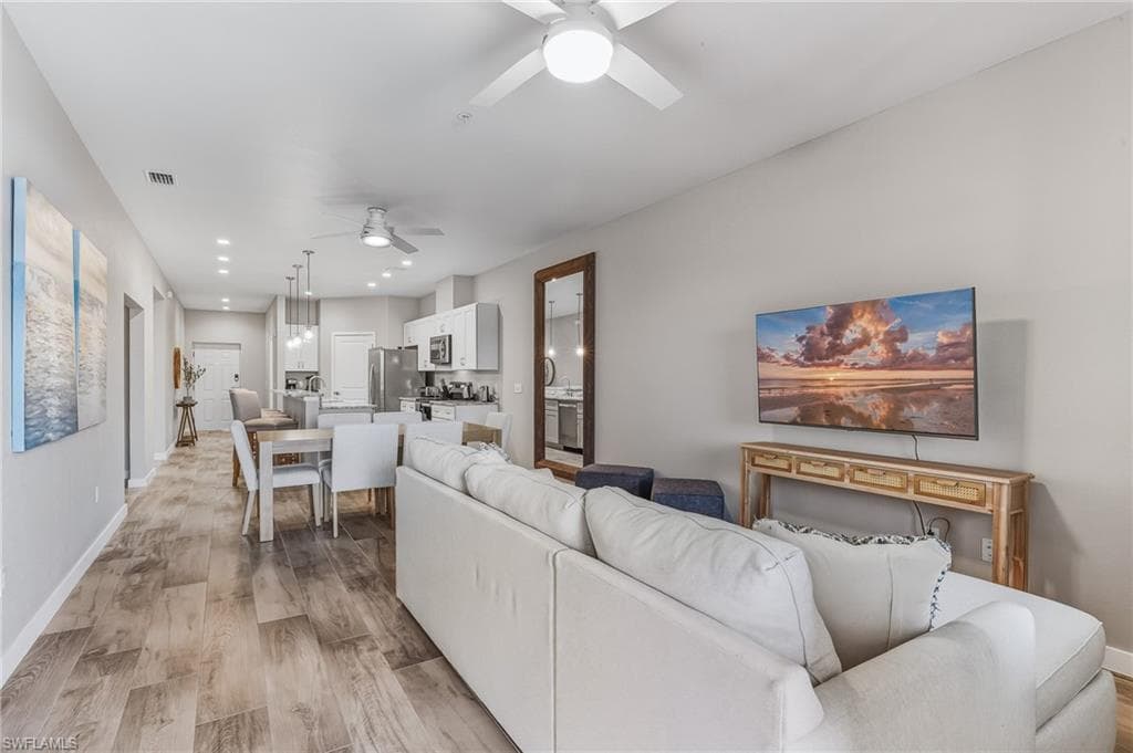 Living area featuring light wood finished floors, a ceiling fan, and recessed lighting