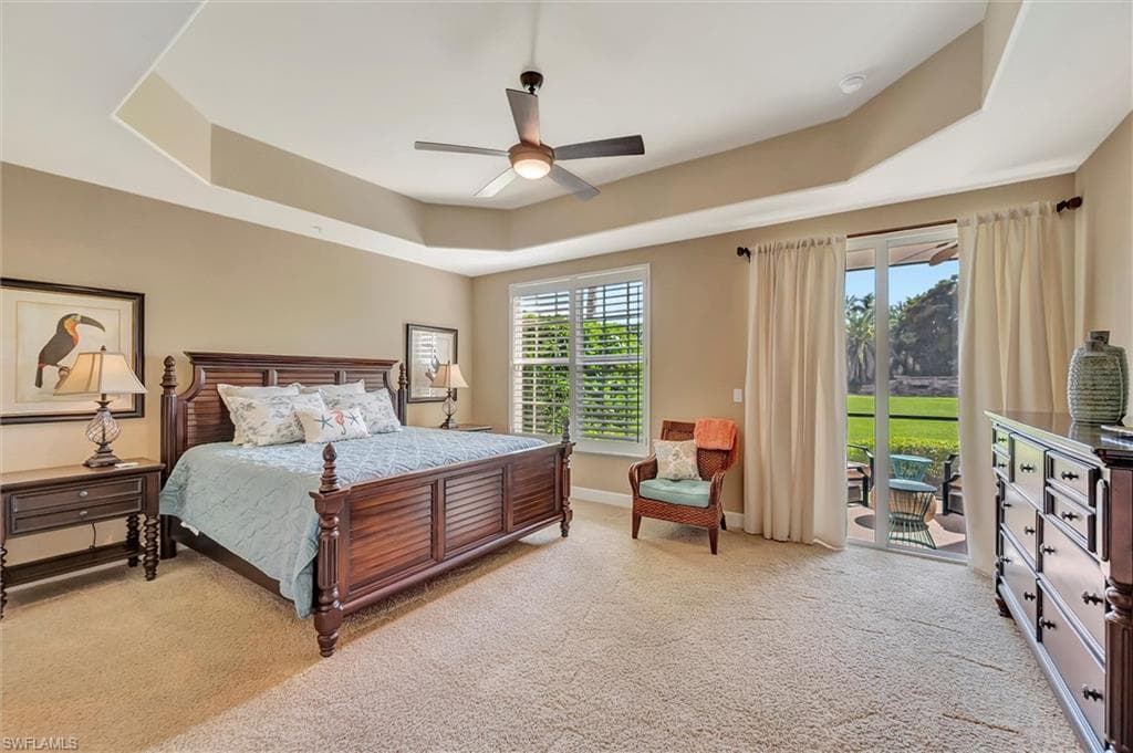 Bedroom featuring a raised ceiling, light carpet, ceiling fan, and access to exterior
