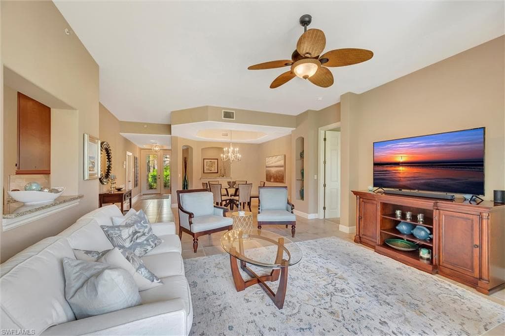Living area with arched walkways, a ceiling fan, and a chandelier