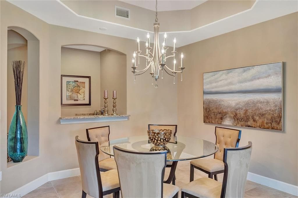 Dining area with light tile patterned floors, a chandelier, and arched walkways