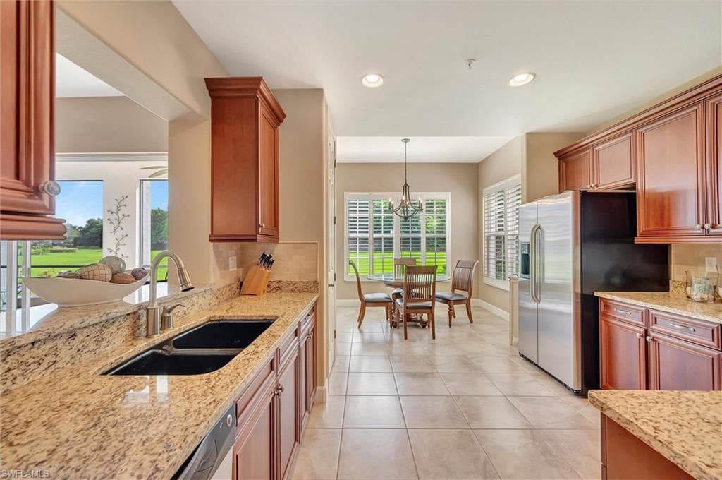 Kitchen featuring light stone countertops, hanging light fixtures, light tile patterned floors, decorative backsplash, and recessed lighting