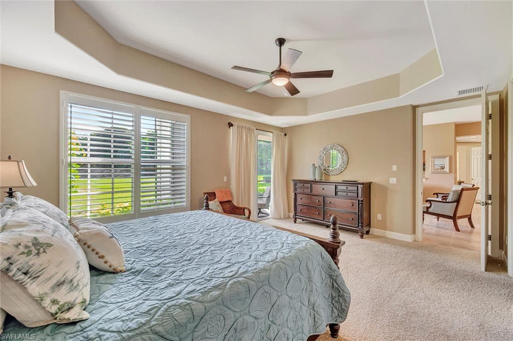 Carpeted bedroom with a tray ceiling, ceiling fan, and access to outside