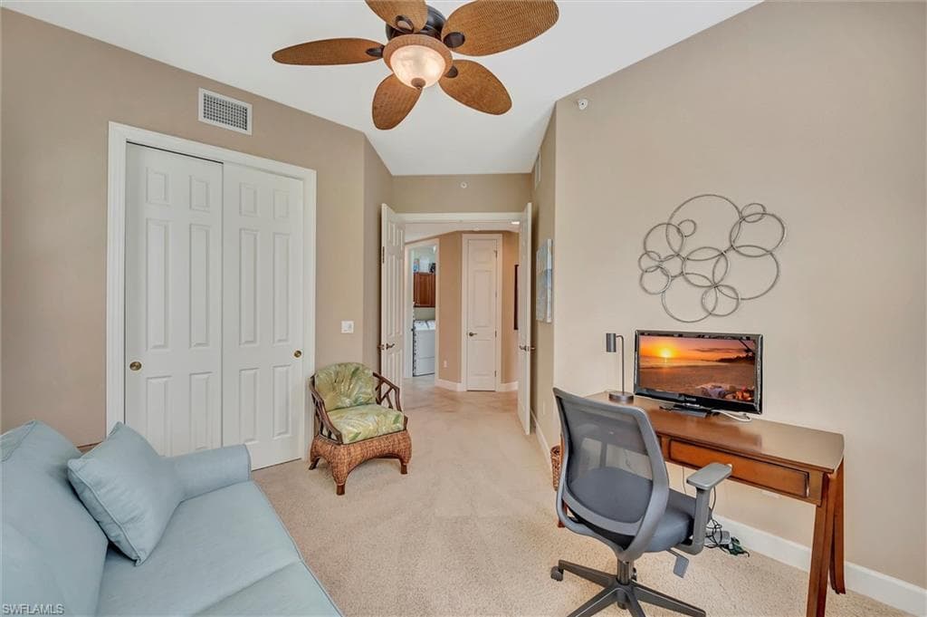 Carpeted office space featuring a ceiling fan and baseboards