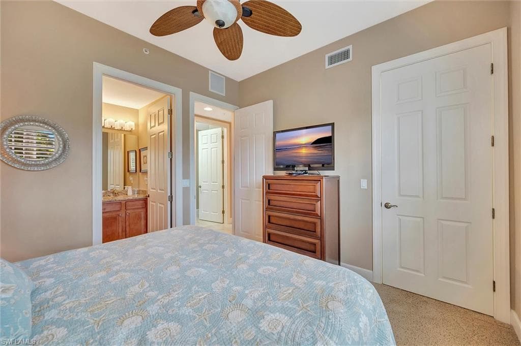Bedroom with light carpet, ceiling fan, and connected bathroom