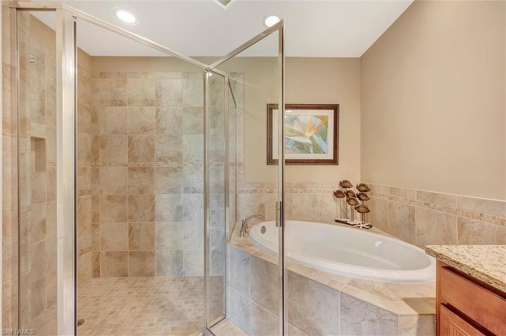 Bathroom featuring a garden tub, vanity, a stall shower, and recessed lighting