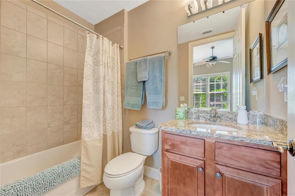 Bathroom featuring shower / bath combination with curtain, vanity, and a ceiling fan