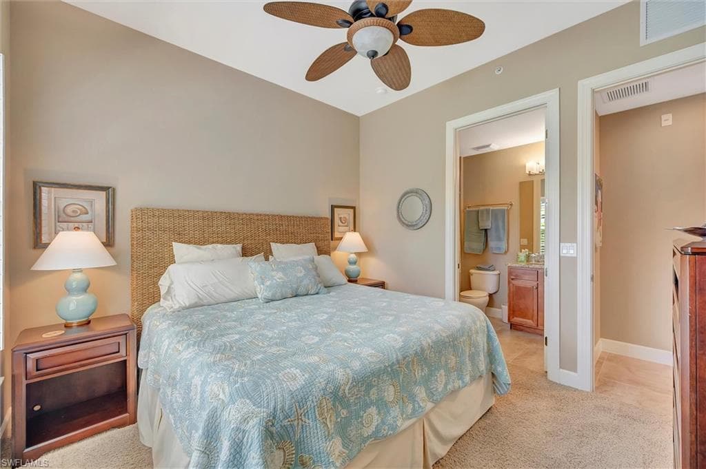 Bedroom featuring light carpet, a ceiling fan, and connected bathroom