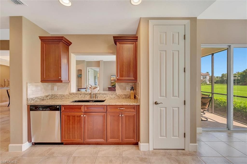 Kitchen with dishwasher, light tile patterned floors, light stone counters, brown cabinets, and recessed lighting