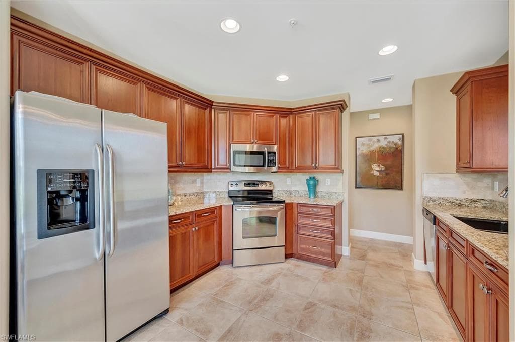 Kitchen featuring stainless steel appliances, light stone counters, tasteful backsplash, and recessed lighting