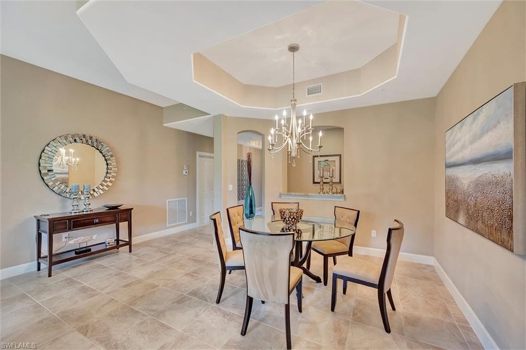 Dining room with a chandelier, a tray ceiling, and light tile patterned floors