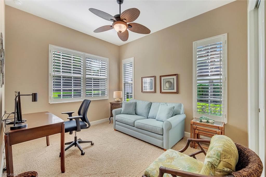 Carpeted home office with healthy amount of natural light and a ceiling fan