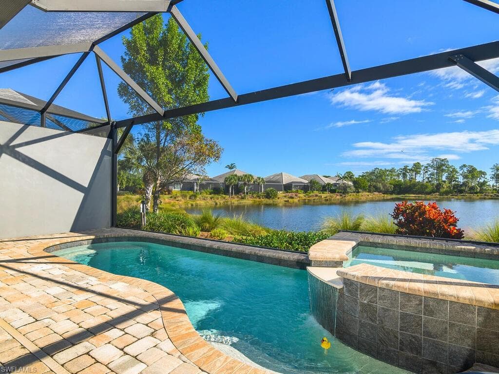 View of swimming pool with a lanai, a water view, a patio area, and a pool with connected hot tub