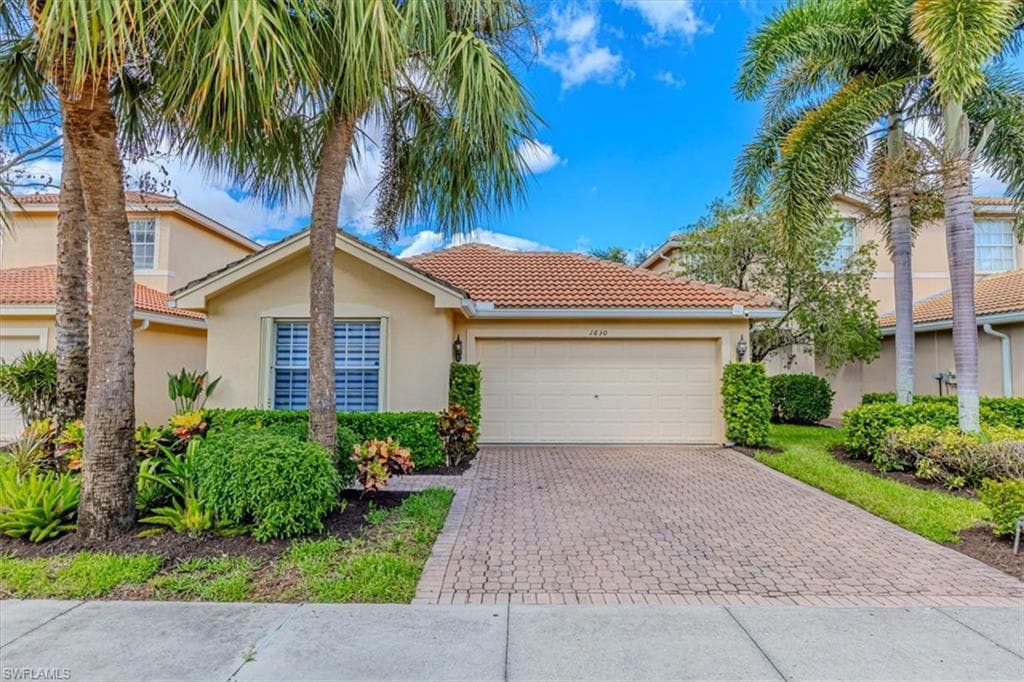 View of front of home featuring a tiled roof, stucco siding, decorative driveway, and an attached garage
