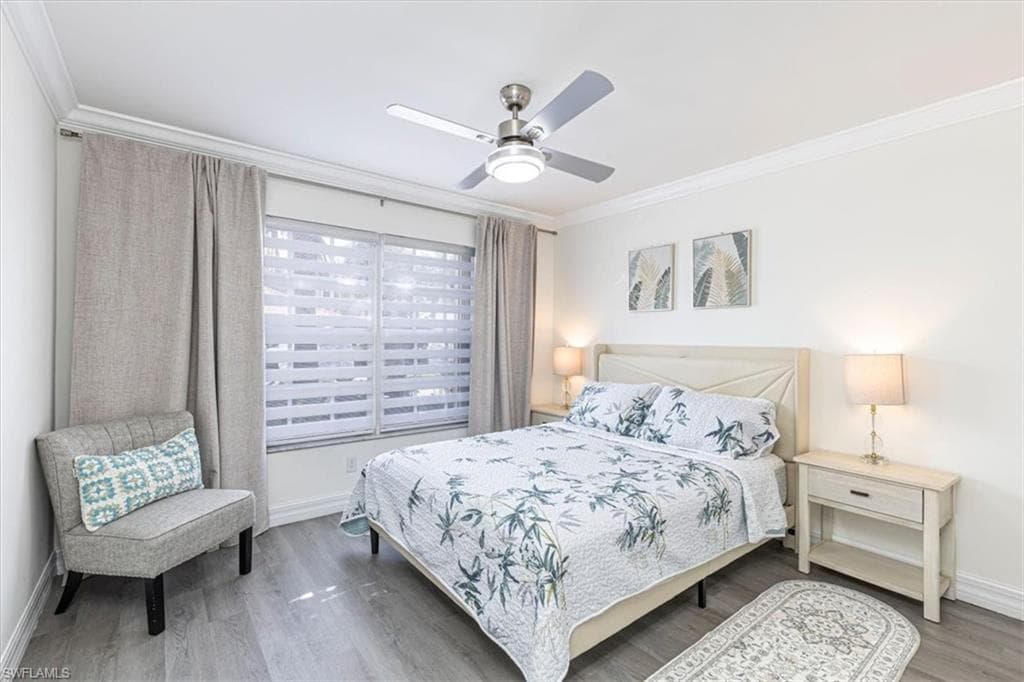 Bedroom with crown molding, wood finished floors, and a ceiling fan