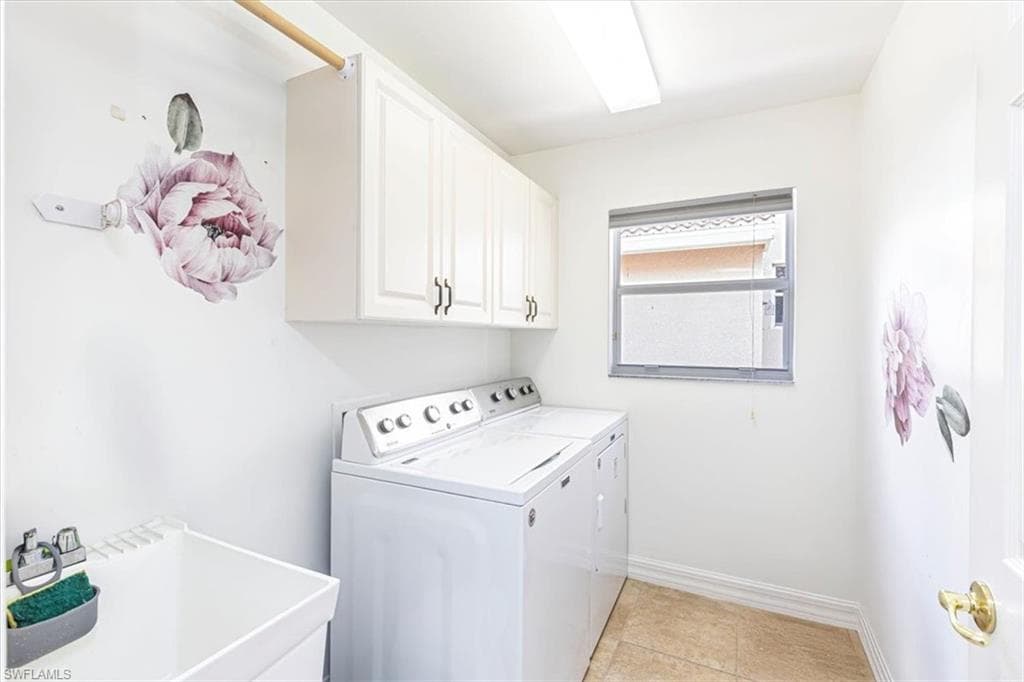 Washroom featuring light tile patterned flooring, separate washer and dryer, and cabinet space