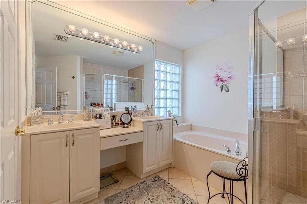 Bathroom with a stall shower, light tile patterned floors, a bath, and double vanity