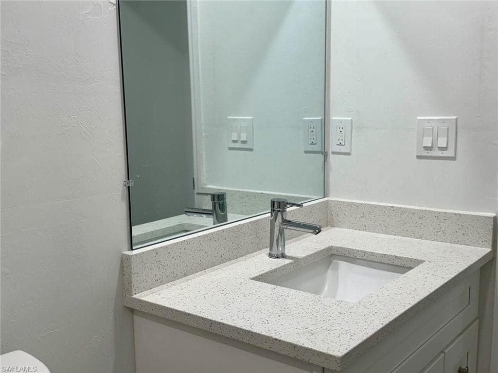 Half bathroom featuring vanity and a textured wall
