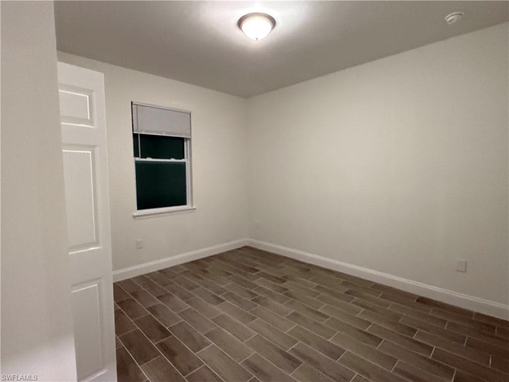 Empty room with baseboards and wood finish floors