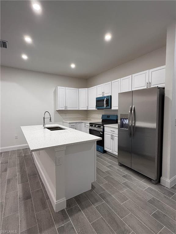 Kitchen featuring stainless steel appliances, wood tiled floors, white cabinetry, recessed lighting, and light stone counters