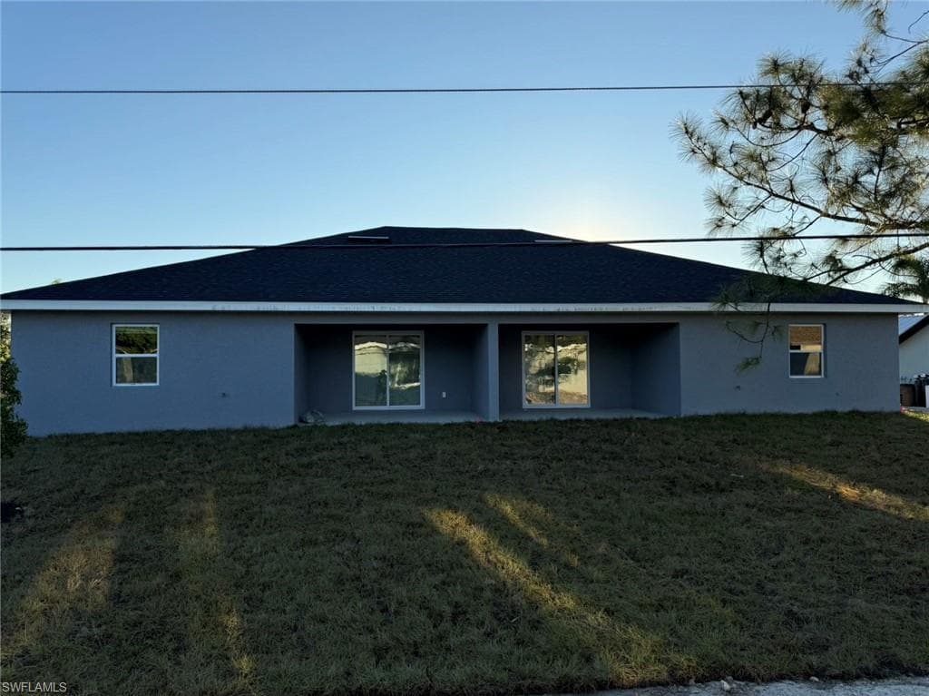 Back of property with stucco siding and a lawn