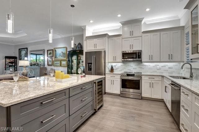 featuring wine cooler, decorative backsplash, Cambria Quartz counters, upgraded stainless steel appliances, lower sized gray cabs with additional storage and pull outs