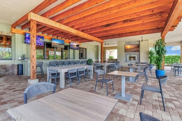 View of patio with outdoor dining area and a warm lit fireplace