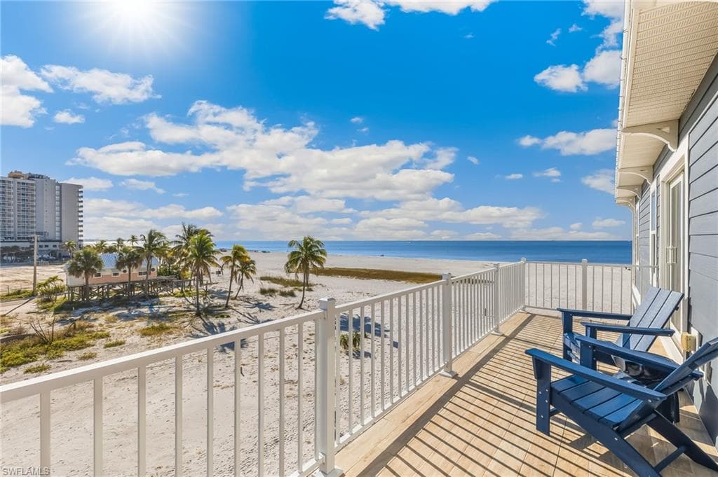 Balcony featuring view of water and beach
