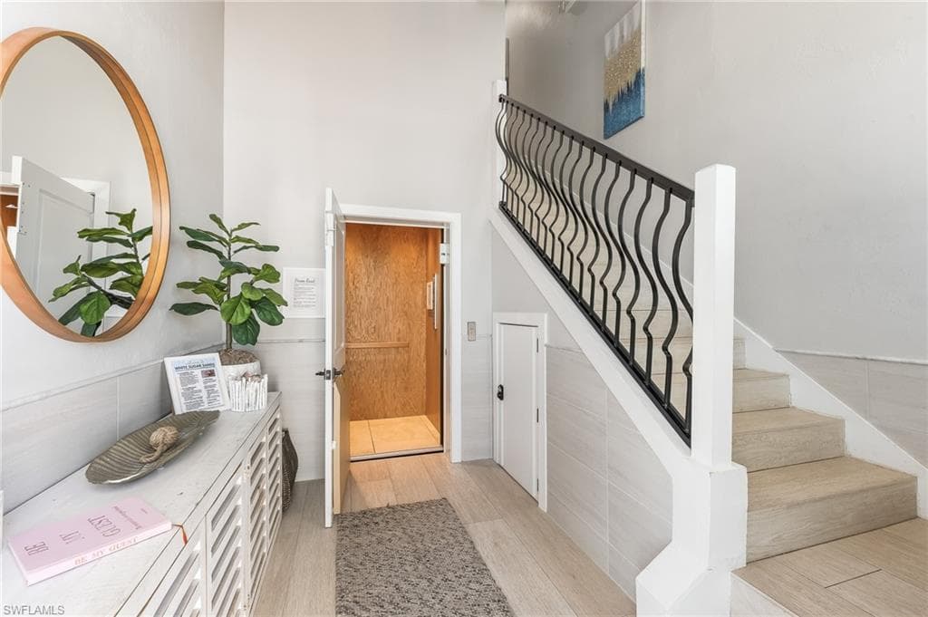 Stairway featuring wood finished floors and a towering ceiling