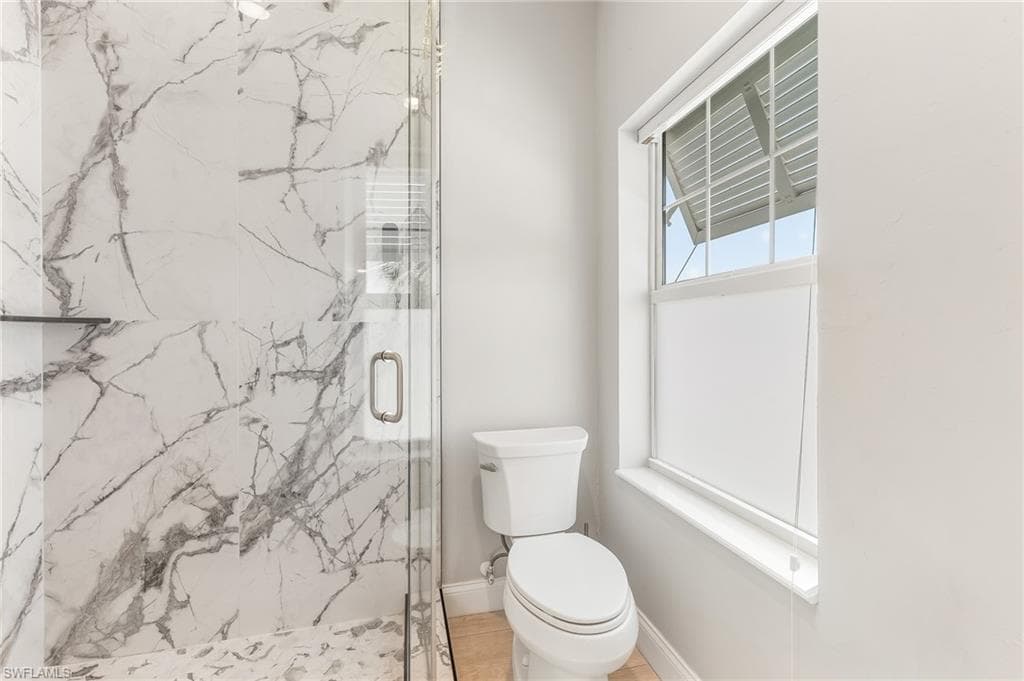 Bathroom featuring a marble finish shower and toilet