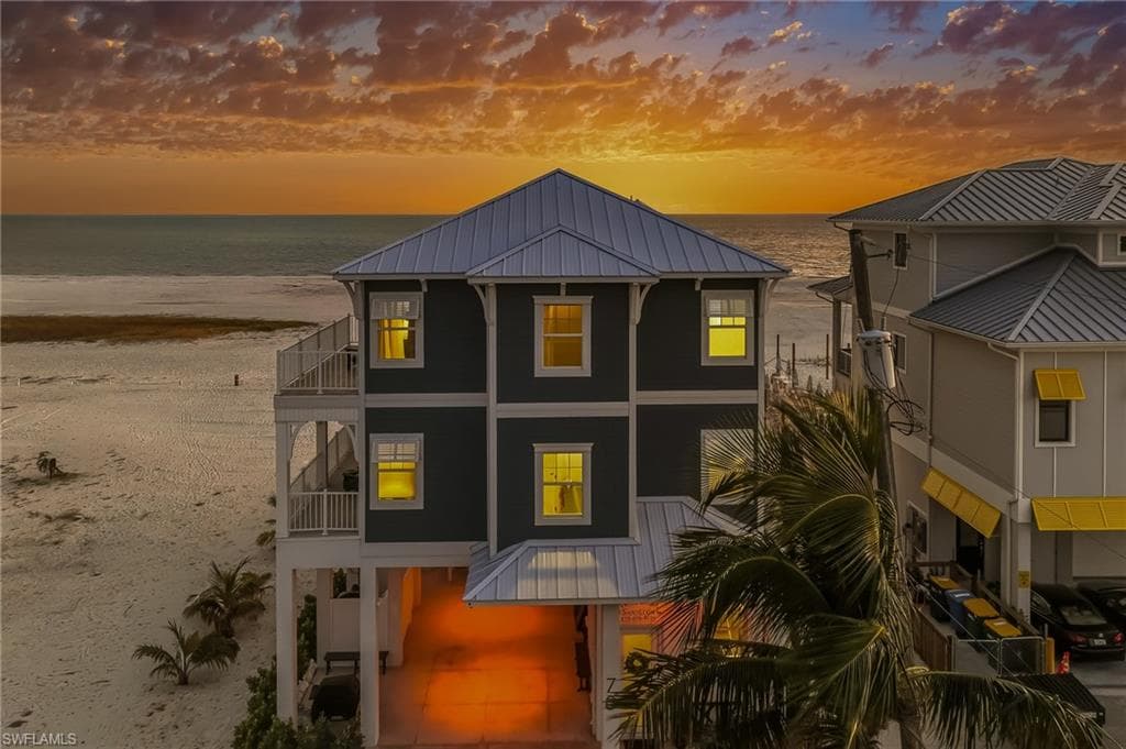 Rear view of property with a metal roof, a standing seam roof, a water view, and a balcony