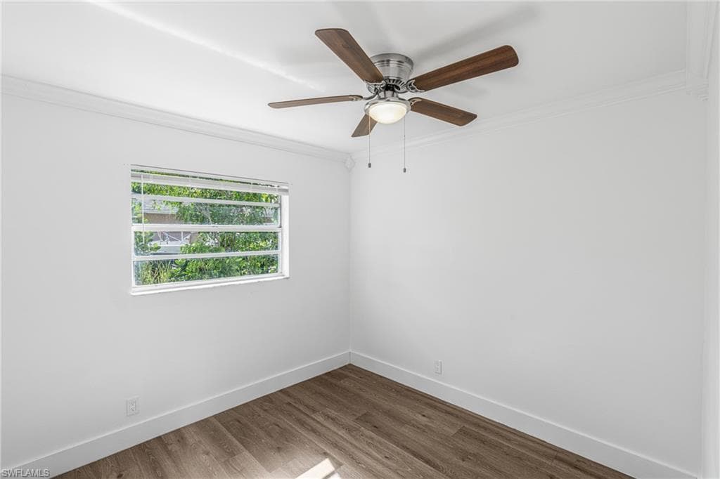 Empty room featuring ornamental molding, wood finished floors, and ceiling fan
