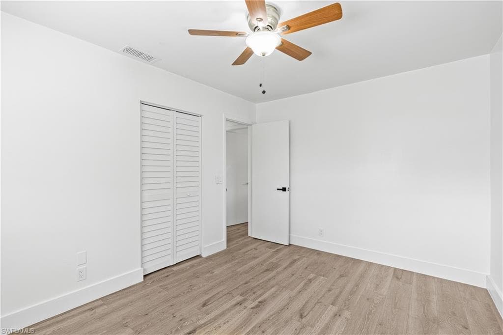 Unfurnished bedroom with light wood-style floors, a ceiling fan, and a closet