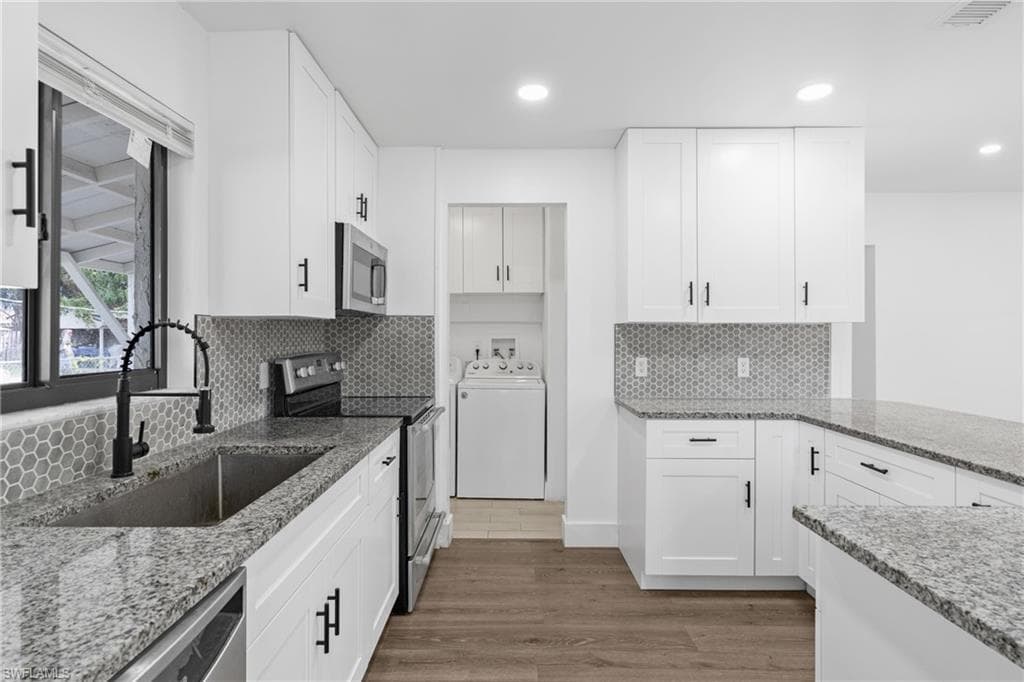 Kitchen with light stone counters, stainless steel appliances, white cabinetry, light wood finished floors, and recessed lighting