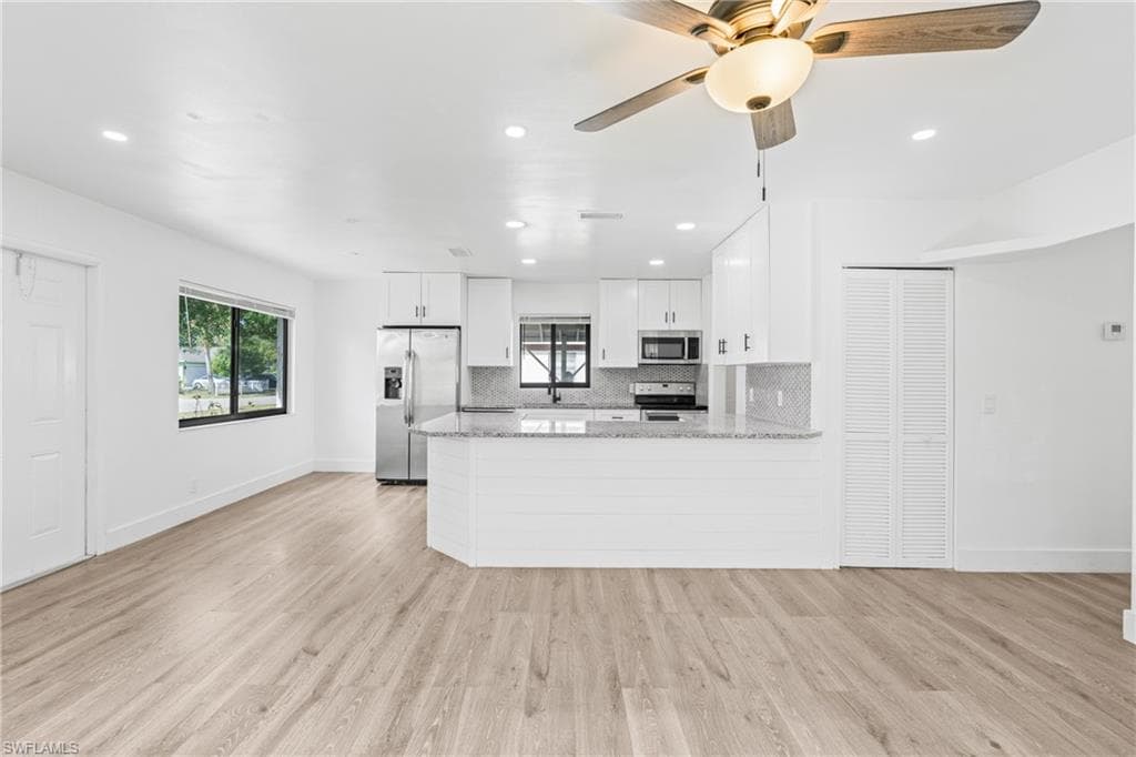 Kitchen featuring white cabinets, decorative backsplash, a peninsula, light wood finished floors, and recessed lighting
