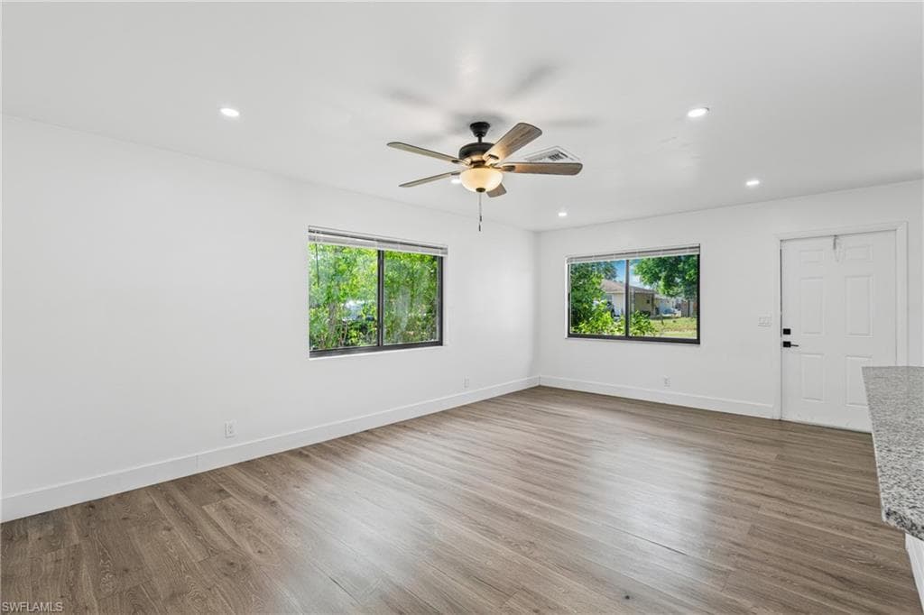 Spare room featuring dark wood-style floors, healthy amount of natural light, recessed lighting, and ceiling fan