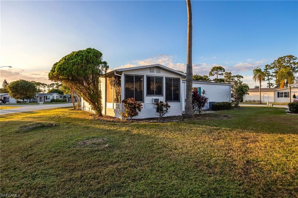 View of side of property with a yard and a sunroom