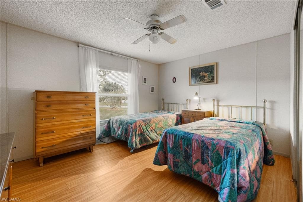 Bedroom with light wood-type flooring, a textured ceiling, and a ceiling fan
