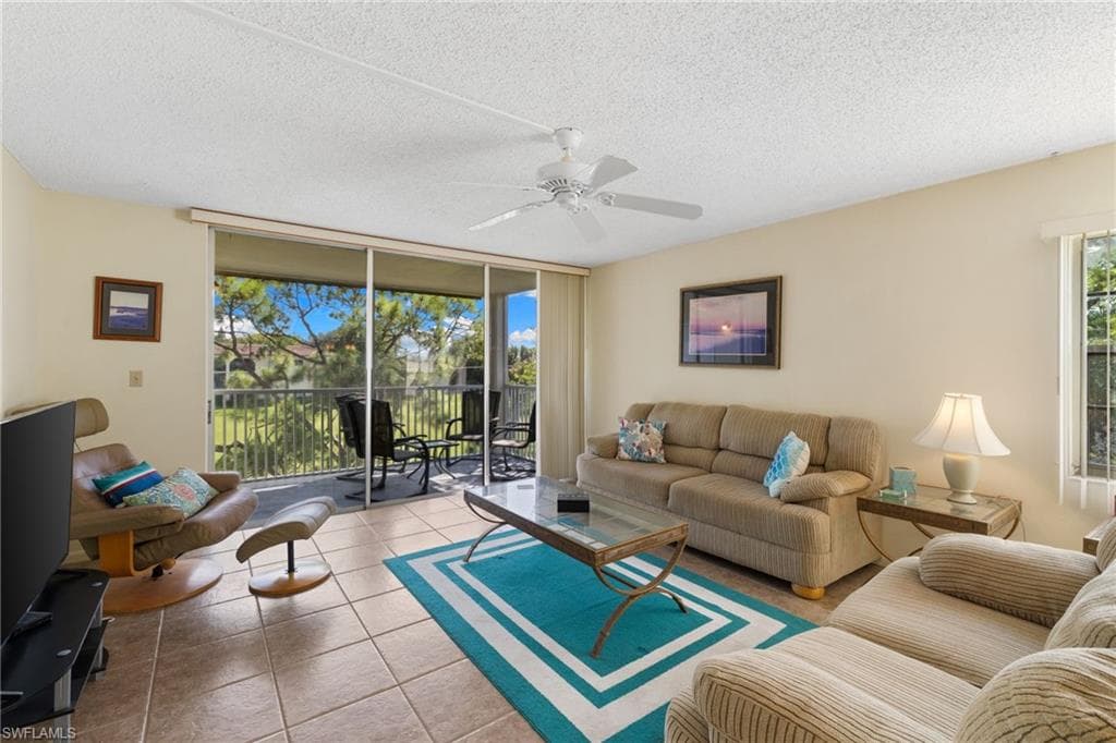 Tiled living area featuring floor to ceiling windows, a textured ceiling, and ceiling fan