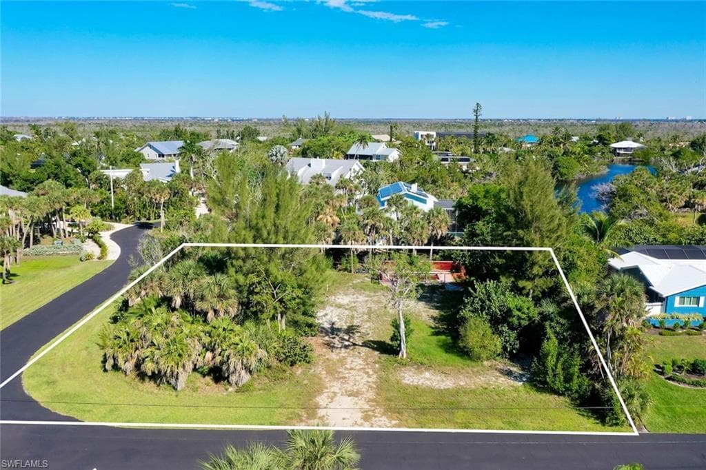 Aerial perspective of suburban area with property parcel outlined and a tree filled landscape