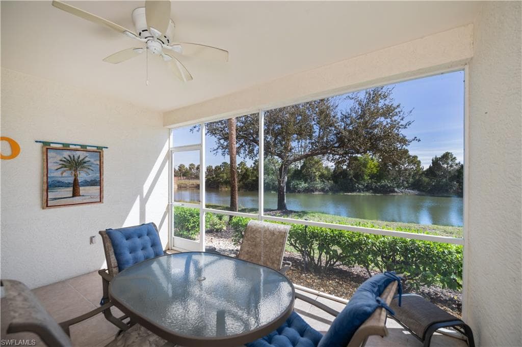 Sunroom with a textured wall, a water view, and view of scattered trees