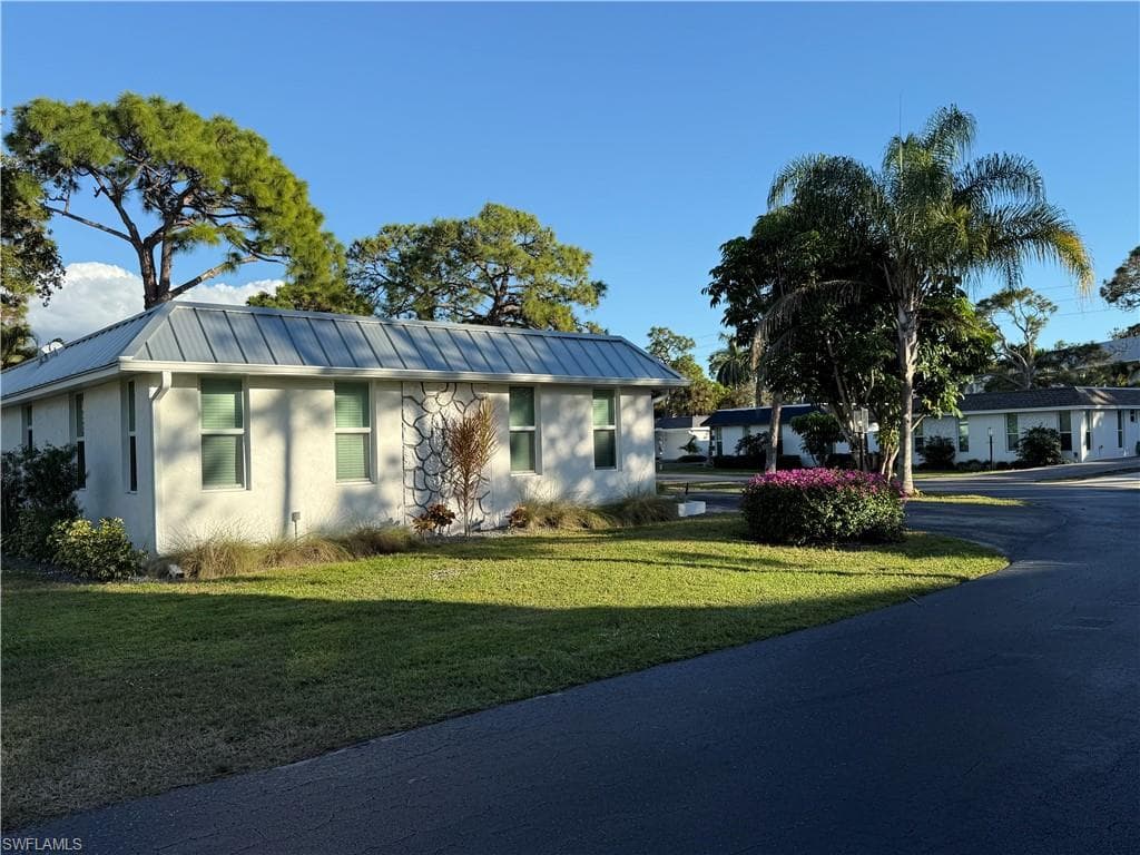 Ranch-style house featuring a metal roof, a front lawn, stucco siding, and a standing seam roof